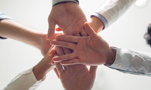 Below view of multiethnic business team stacking hands showing support, success and corporate spirit